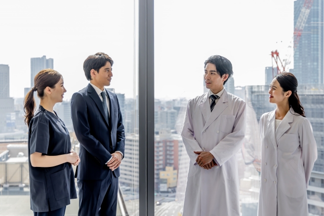 窓際で話し合うビジネスマンと医師たち